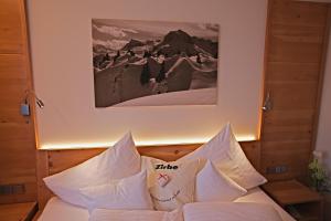 uma cama com almofadas brancas e uma fotografia na parede em Pension Walserheim em Lech am Arlberg