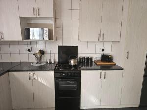 a kitchen with a black stove and white cabinets at Amberdale Estate Self Catering in Queenstown