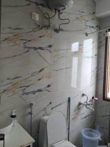 a bathroom with a toilet and a marble wall at Cozy Cove - Newly built 3BHK Duplex with rare valley view in Shimla