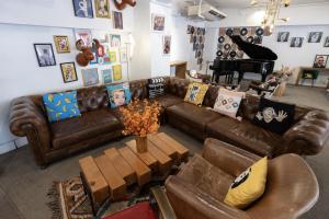 a living room with a brown leather couch and a piano at Mini Central in Hong Kong