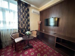 una camera d'albergo con tavolo e TV a schermo piatto di ОРДА a Shymkent