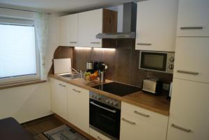 レンゲンフェルトにあるHaus Elenaの白いキャビネット、シンク、電子レンジ付きのキッチンが備わります。