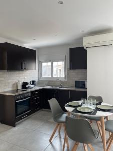 a kitchen with black cabinets and a table and chairs at Athenian Modern 2BD Apt next to Metro Panepistimio in Athens