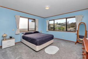- une chambre avec des murs bleus et un lit avec un miroir dans l'établissement Seascape Sanctuary - Okiato Holiday Home, à Russell