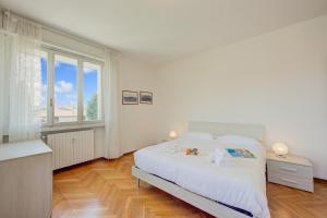 a white bedroom with a bed and a window at Margherita near lake - Family Friendly - Happy Rentals in Toscolano Maderno