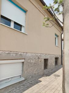 biały budynek z dwoma drzwiami garażowymi obok chodnika w obiekcie Kursumlija w mieście Kuršumlija