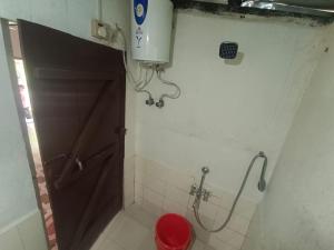 La salle de bains est pourvue d'une porte marron et de toilettes rouges. dans l'établissement Ibankordor Jungle Resort, à Cherrapunji