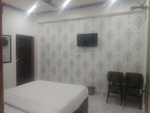 a bedroom with a bed and a tv on a wall at Radhika Hotel in Jaipur