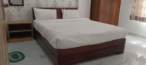Una cama con sábanas blancas y almohadas en un dormitorio en Radhika Hotel, en Jaipur