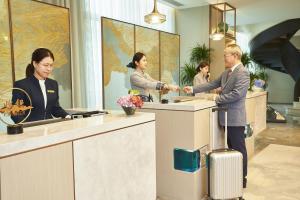 a man and woman shaking hands at a reception counter at LN Dongfang Hotel, Pazhou in Guangzhou