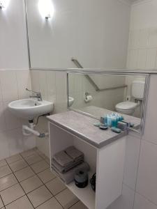 a bathroom with a sink and a toilet and a mirror at The Saltbush Motor Inn in Hay