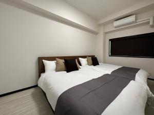 比治山町にあるLuxes - 2Br Apt for 10ppl Very Good Locationのテレビ付きの客室で、白い大型ベッド1台が備わります。