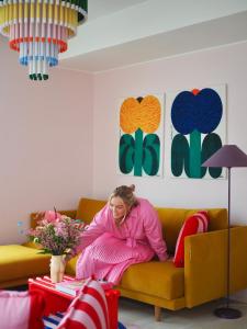 a woman sitting on a couch in a living room at Candy-Colored Two-Room Condo with Sweet views in Helsinki