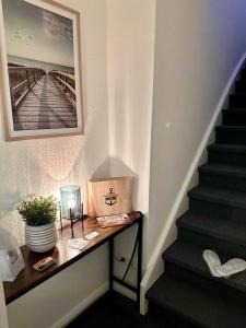 eine Treppe mit einem Tisch und einem Bild an der Wand in der Unterkunft Ferienwohnung Deichblick in Emden