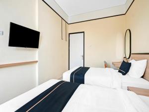 2 camas en una habitación de hotel con TV de pantalla plana en Homi Stay, en Solo