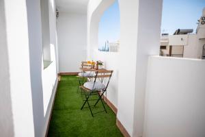 Cette petite chambre dispose d'une moquette verte et d'une table avec des chaises. dans l'établissement La Marina Beach 3 bedrooms Sun & Golf, à Torre de Benagalbón
