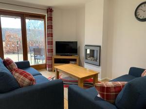 Sala de estar con 2 sofás azules y TV en Aldhelm Cottage en Beckington