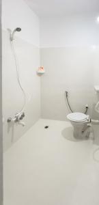 a white bathroom with a toilet and a shower at Surya residency in Bangalore