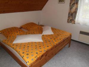 a bed with an orange comforter in a bedroom at Familienfreundliches Ferienhaus - b64026 in Marktgraitz