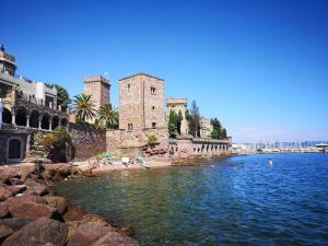 a group of people on a beach next to a castle at Hôtel de la Corniche d'Or in Mandelieu-La Napoule