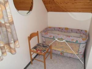a small bedroom with a crib and a chair at Ferienhaus im schönen Frankenland in Marktgraitz