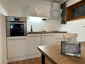 cocina con armarios blancos y mesa de madera en Appartement Tegelberg, en Steingaden