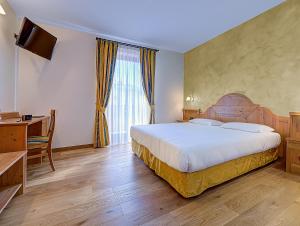 Habitación de hotel con cama grande y escritorio. en Hotel Garni La Vigna, en San Michele allʼAdige