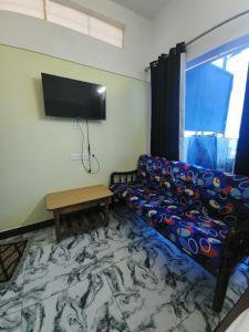 a living room with a couch and a flat screen tv at Paradise Harmony Beach Resort in Singānallūr
