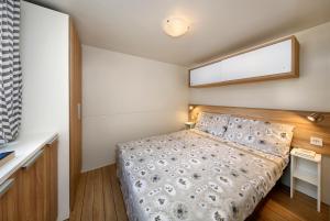 a small bedroom with a bed and a window at Albatross Mobile Homes on Camping Bella Austria in Sankt Peter am Kammersberg