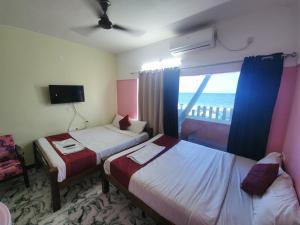a hotel room with two beds and a window at Paradise Harmony Beach Resort in Singānallūr