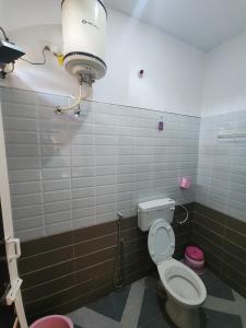 a bathroom with a toilet and a light on the wall at Paradise Harmony Beach Resort in Singānallūr