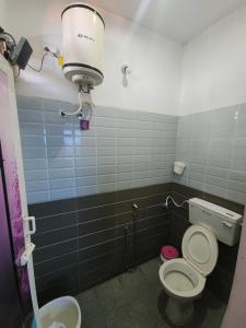 a bathroom with a toilet and a light on the wall at Paradise Harmony Beach Resort in Singānallūr