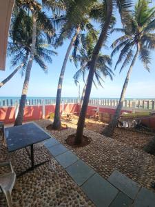 a picnic table on the beach with palm trees at Paradise Harmony Beach Resort in Singānallūr