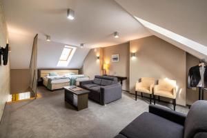 une chambre d'hôtel avec un lit, un canapé et des chaises dans l'établissement Hotel Białowieski Conference, Wellness & SPA, à Białowieża