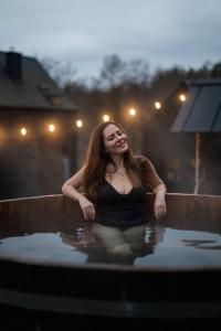 Domki Momenty في Słajszewo: وجود امرأة جالسة في المسبح ليلا