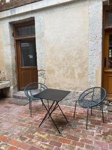 two chairs and a table in front of a building at Le Patio in Lisieux