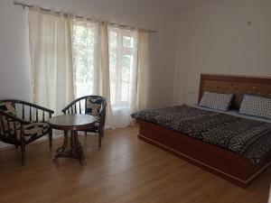 1 dormitorio con 1 cama, mesa y sillas en Rumi Cafe and Stay, en Leh