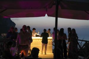 Un grupo de personas de pie alrededor de un bar bajo una carpa. en Villa Galeotta, en Marina Grande