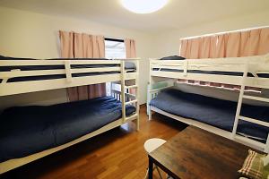 a room with three bunk beds and a table at TOKYO MY HOME in Tokyo
