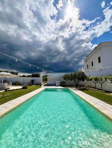 a swimming pool with blue water in front of a white building at Masseria Mammella in Monopoli