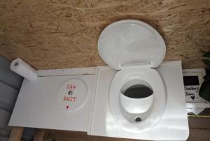a bathroom with a white toilet with a sign on it at The Buddha Shed in Hindmarsh Valley