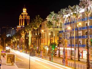 a city street at night with palm trees and a building at Apartment Eteri in Batumi