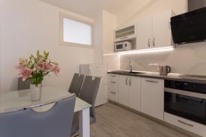 a kitchen with white cabinets and a table with a vase of flowers at Villa Stonehouse 2 in Milna
