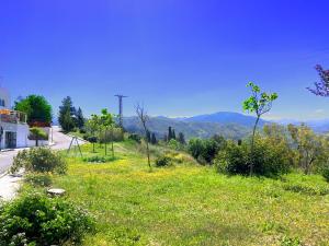 un campo de césped verde con montañas en el fondo en CASA LOS ABETOS cerca de la Alhambra y Sierra Nevada, en Cenes de la Vega