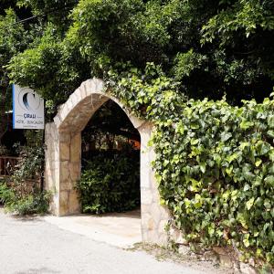 a stone archway with a green hedge at Cirali Hotel in Cıralı
