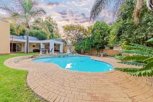 a swimming pool with a brick walkway around a house at Homely Haven in Roodepoort