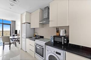 a kitchen with white cabinets and a table in it at Luxurious Studio with Stunning Views at Damac Celestia in Dubai