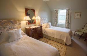 a bedroom with two beds and a mirror and a chair at Inveroykel Lodge at Rosehall in Rosehall