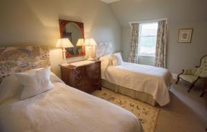RosehallにあるInveroykel Lodge at Rosehallのベッドルーム1室(ベッド2台、鏡、椅子付)
