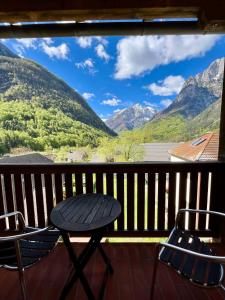 een tafel en stoelen op een balkon met uitzicht op de bergen bij Hotel Alpine in Log pod Mangartom